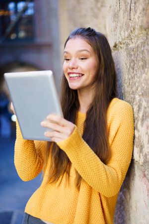A Joyful Young Woman is Engaged with Her Tablet While in a Bustling Urban Setting
