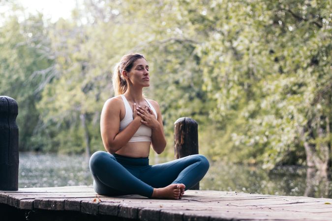 Woman meditating in nature near a lake