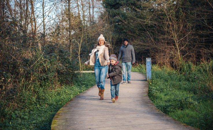 Mother and father in fall coats walking with children in forest