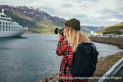 Woman with backpack takes photo of cruise ship in port 5oPv84