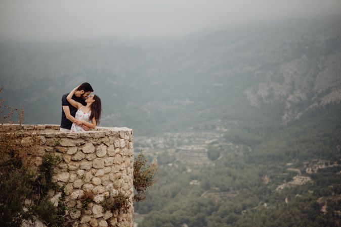 Romantic couple kissing while enjoying countryside view at mountain observation deck