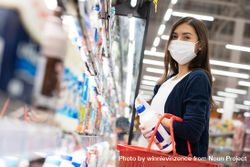Woman picking up items at grocery shopping in surgical mask bEOR65