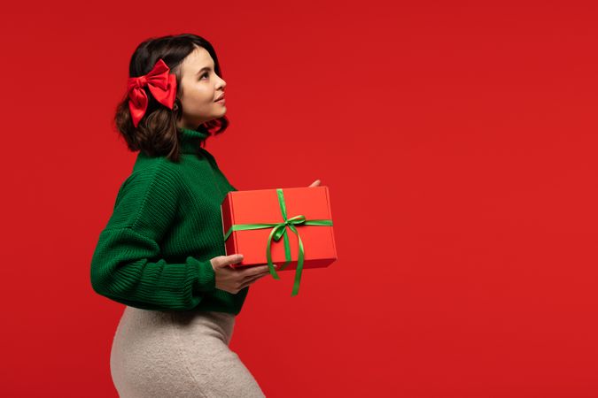 Woman with red bow in hair, holding gift box
