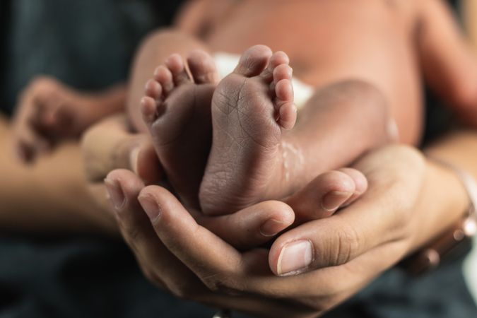 Anonymous mother holding baby feet