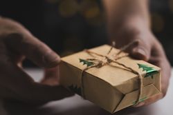 Man holding Christmas gift by wooden table