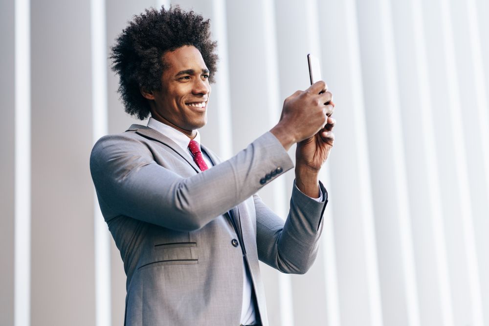 Smiling man taking picture on his phone