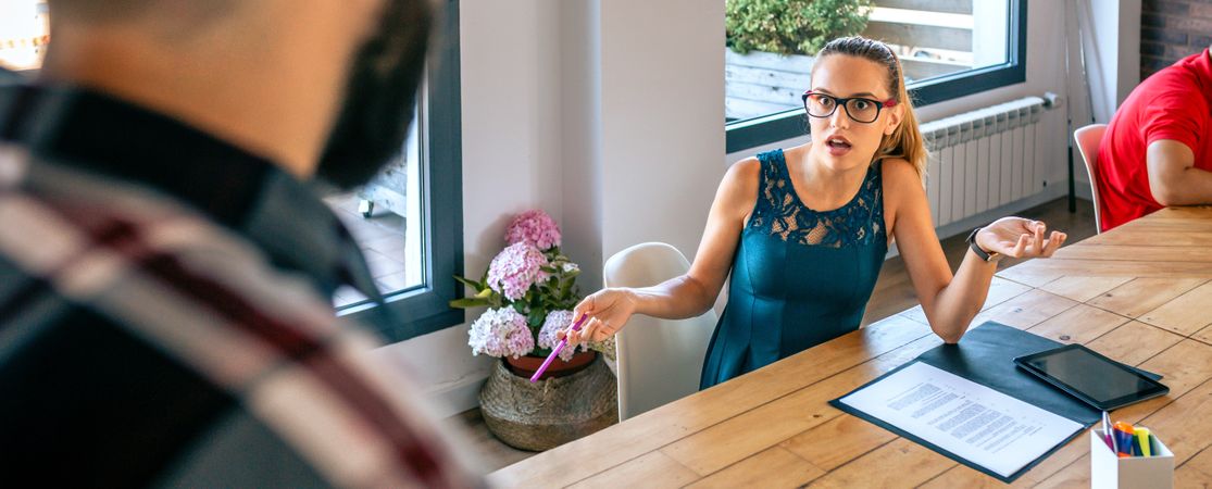 Surprised woman arguing with colleague for problems in coworking