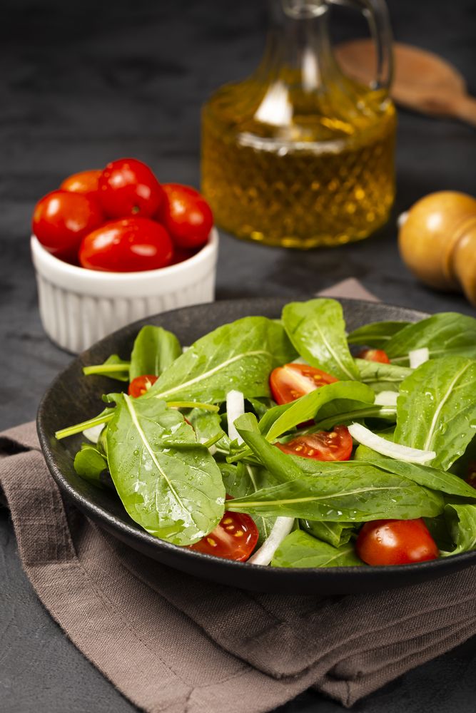 Arugula salad with tomatoes on dark background.