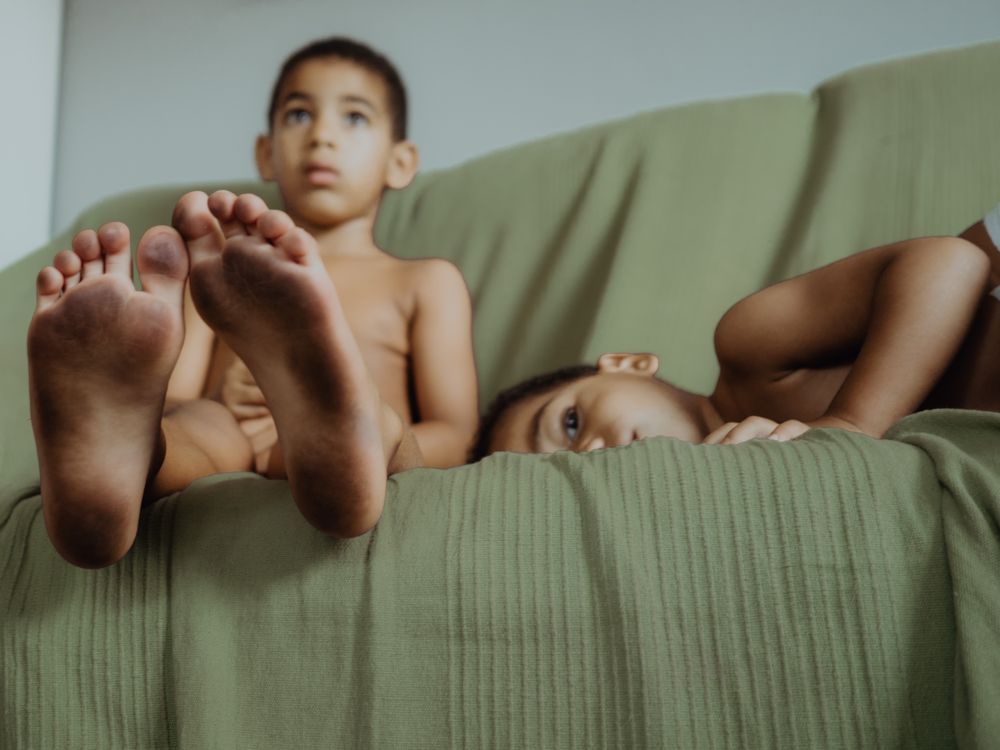 adorable children seat and lying down on the couch with dirty feet