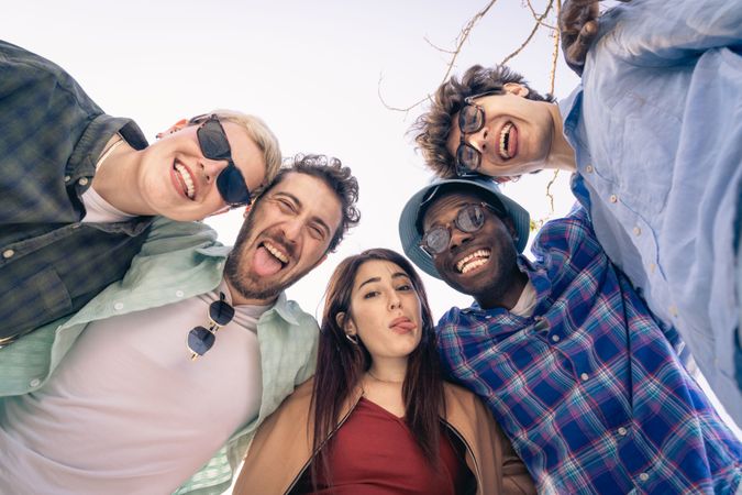 Diverse group of friends making funny faces for a selfie outdoors.