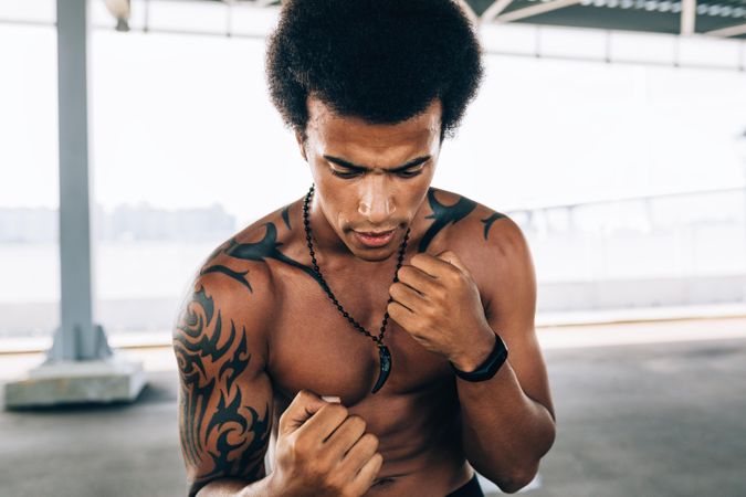 Black male athlete with tattoos doing boxing training outside