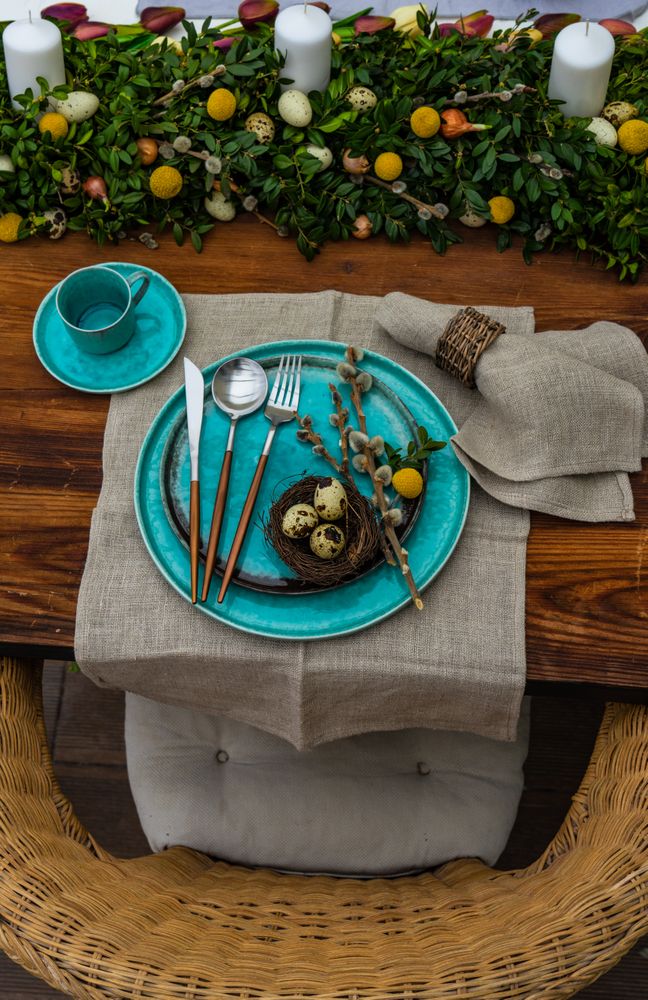 Top view of festive table setting for Easter holiday dinner with speckled eggs in nest