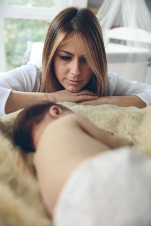 Baby sleeping on a blanket while her mother looks