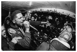 Young male MC passionately rapping into microphone at concert in small venue