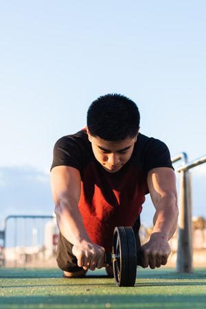 Muscular man doing ab wheel rollout exercise