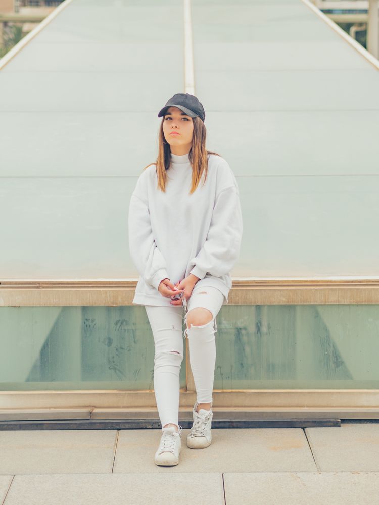 Young woman with glasses standing against wall