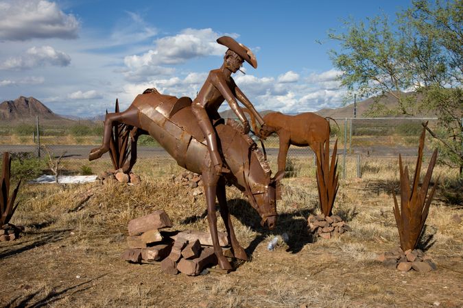 Rusty iron sculpture of cowboy on bucking horse