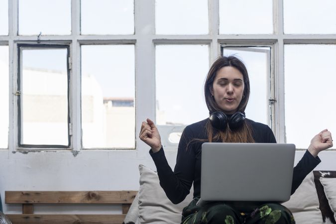 Beautiful Woman sitting on sofa with arms up in front of laptop