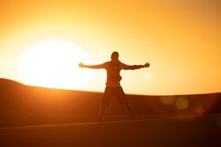 Anonymous traveler in desert during sunset