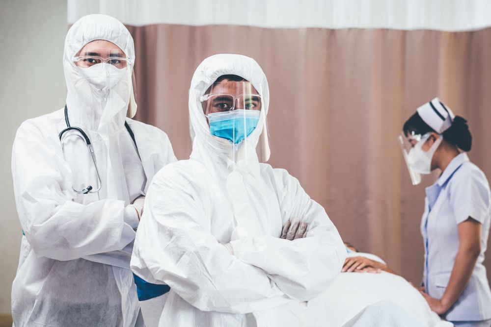 Two medical professional in full PPE with their arms crossed in emergency room