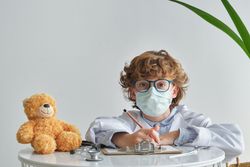 Boy in medical uniform with toy bear during checkup