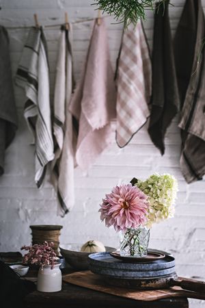 Table with flowers in vase on trays near towels hanging on thread
