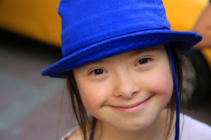 Close up portrait of happy girl with blue hat looking up at camera