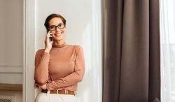 Woman in smart casual outfit smiling while on a cell phone