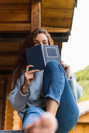 Woman reading book on terrace of house