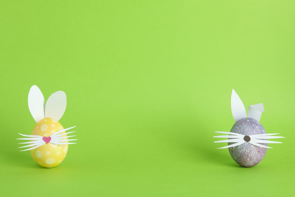 Decorated Easter eggs and cute bunny's ears on color background. Space for text