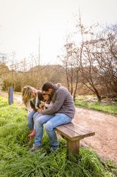 Parents with small daughter with drink on park bench in forest