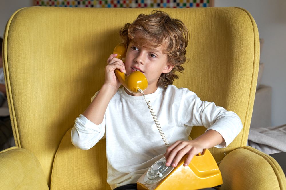 Interested boy speaking on old fashioned wired phone