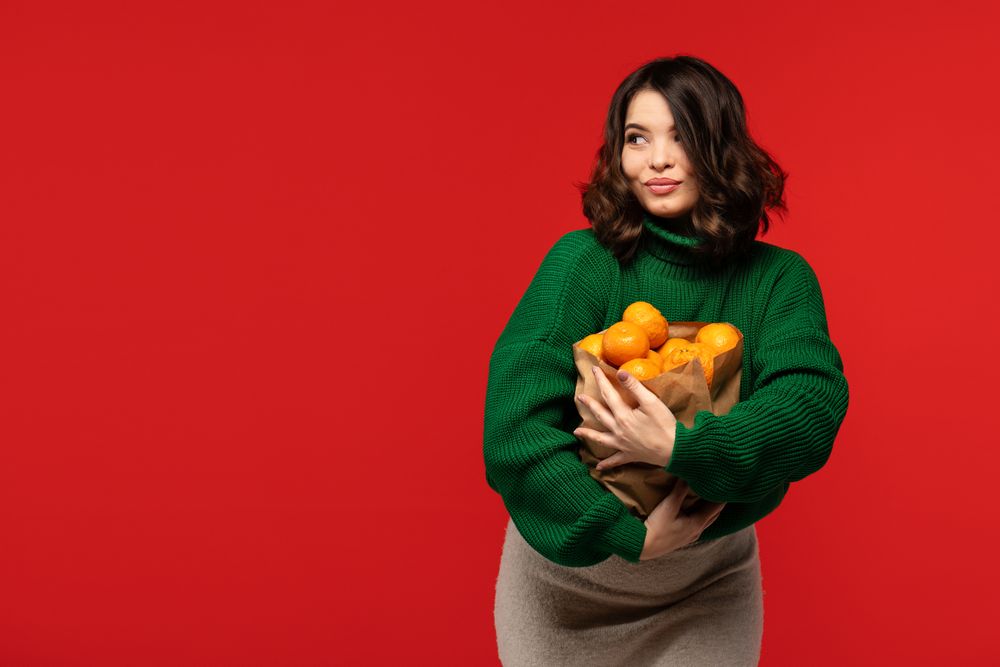 Woman holding paper bag full of fresh tangerines