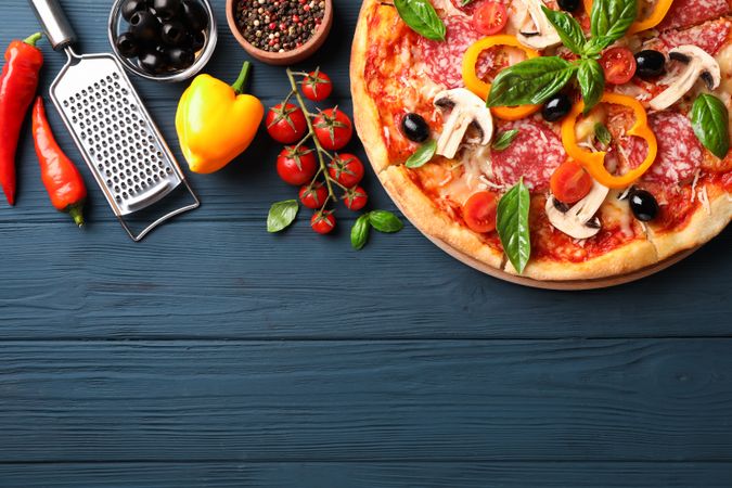 Delicious pizza and ingredients on wooden background, copy space
