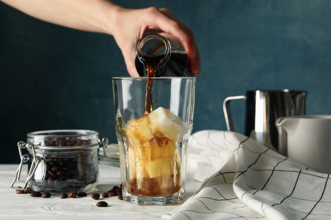 Woman pours a glass of coffee. Composition with ice coffee