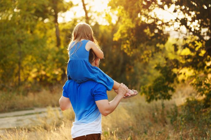 Man and daughter dressed in blue walking along forest path