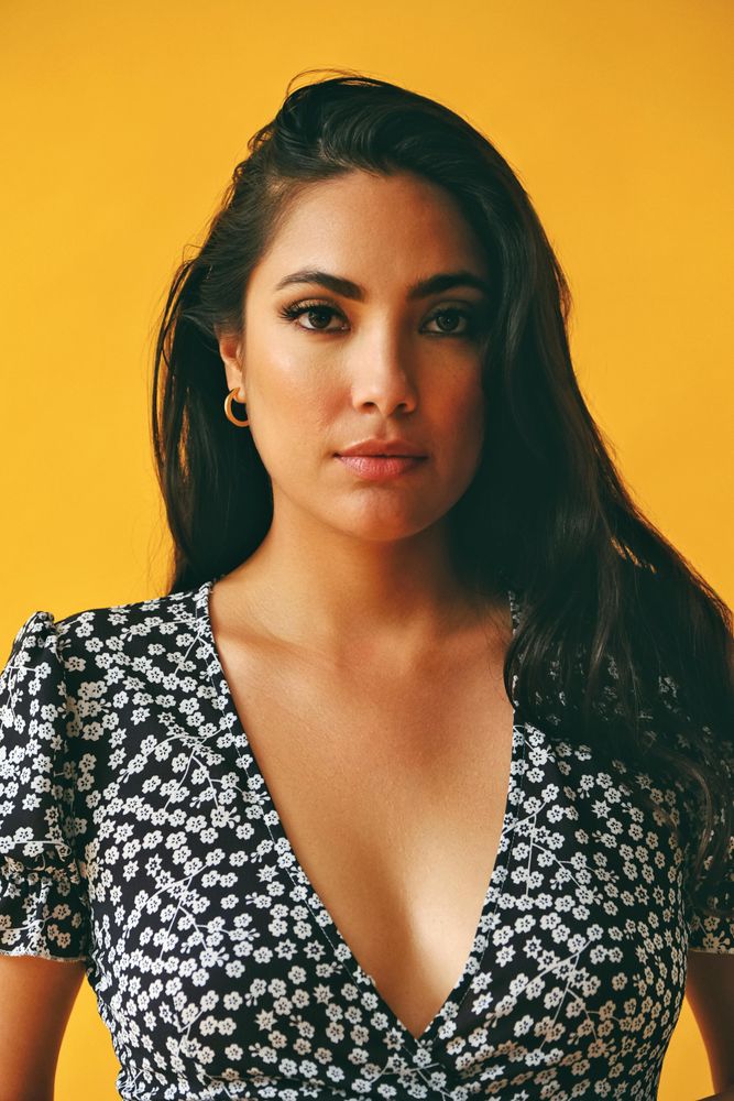 Hispanic woman wearing dress in yellow room, vertical
