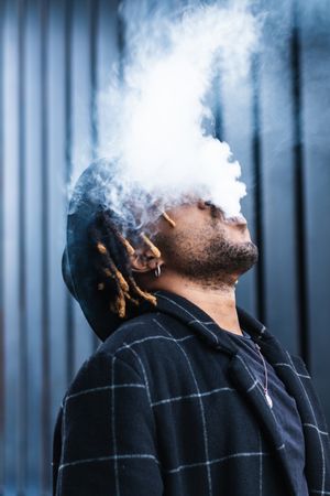 Black man exhaling cloud of smoke on street
