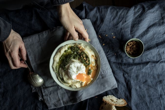 Person holding bowl with cauliflower puree with pesto and eggs