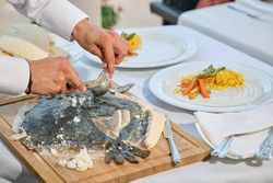 Crop waiter serving flounder on wooden cutting board
