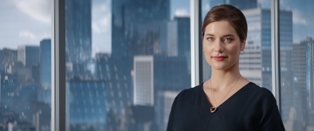 Portrait of White Businesswoman Posing Next to Window in Big City Office with Skyscrapers.