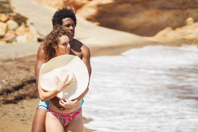 Multiethnic couple hugging on seashore