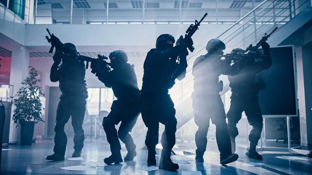 Masked Fireteam of Armed SWAT Police Officers Storm a Bright Seized Office Building with Desks and Computers.