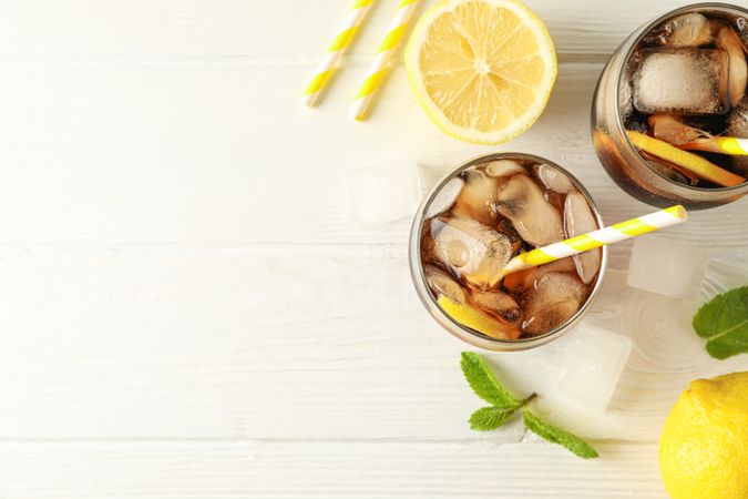 Glasses with cold cola and citrus on wooden background, top view