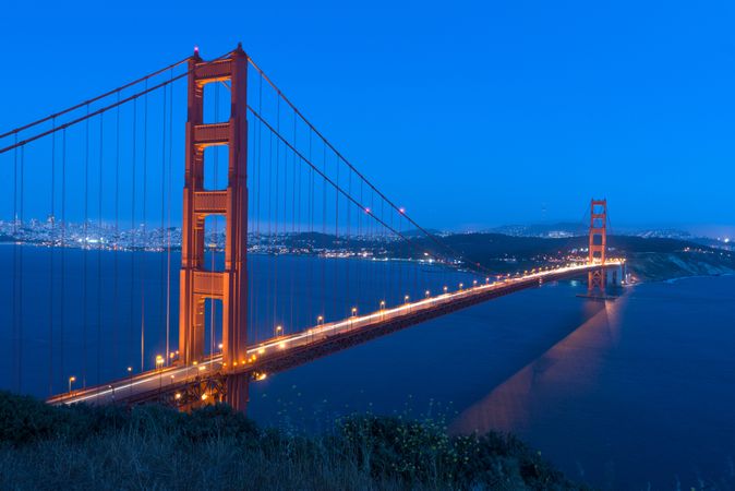 Golden Gate Bridge glowing against dark blue dusky sky
