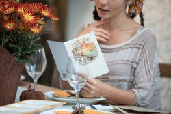 Cropped image of woman sitting in a restaurant reading food menu bxKNd4