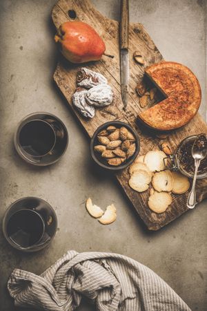 Cheese plate with glasses of red wine, and linen towel on concrete