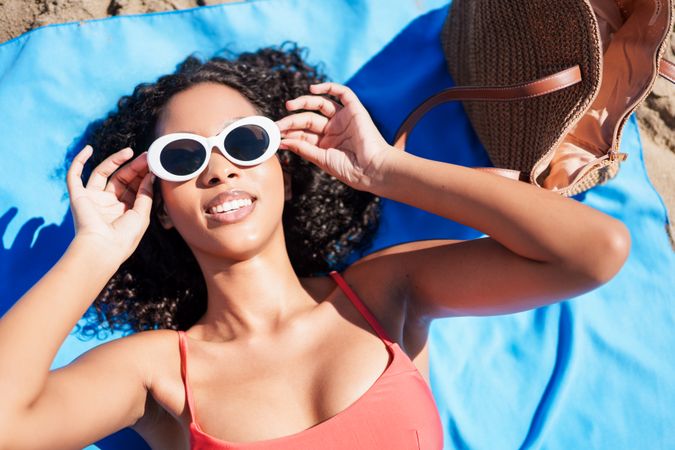 A Young Woman is Thoroughly Enjoying the Warm Sun on the Beach While Wearing Stylish Sunglasses