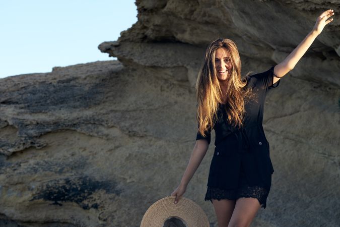 Cheerful woman holding hat in air