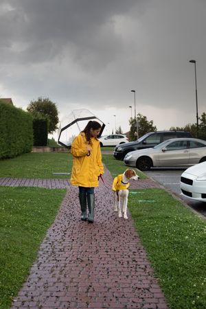 Woman walking with dog in cloak in street